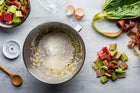 Ingredienti freschi: pezzi di rabarbaro, farina e un uovo per una ricetta estiva leggera, con cucchiaio di legno e pelatura in background.